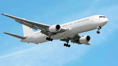 A white twin-engine commercial jet flies in a clear blue sky with landing gear extended.