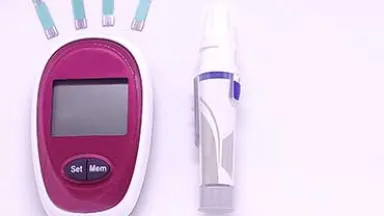 A magenta and white blood glucose meter, a lancing device, and several test strips lie on a white surface.